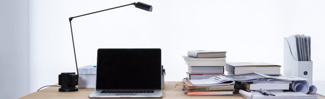 A desk with a computer and notebooks