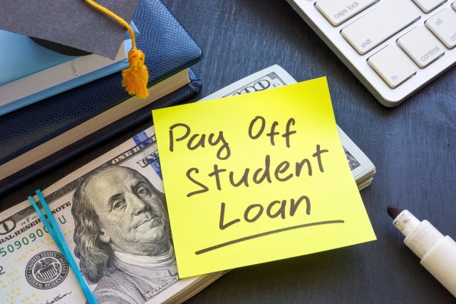 Sticky note reading “Pay off student loan” on top of cash and books, representing student loan refinancing.