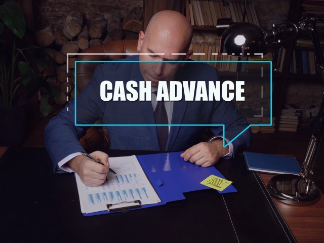 CASH ADVANCE inscription on the screen with a man inspecting market data